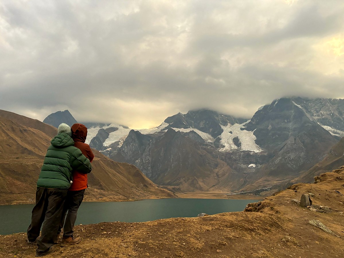 Two hikers looking out over a glacial lake in the Cordillera Huayhuash
